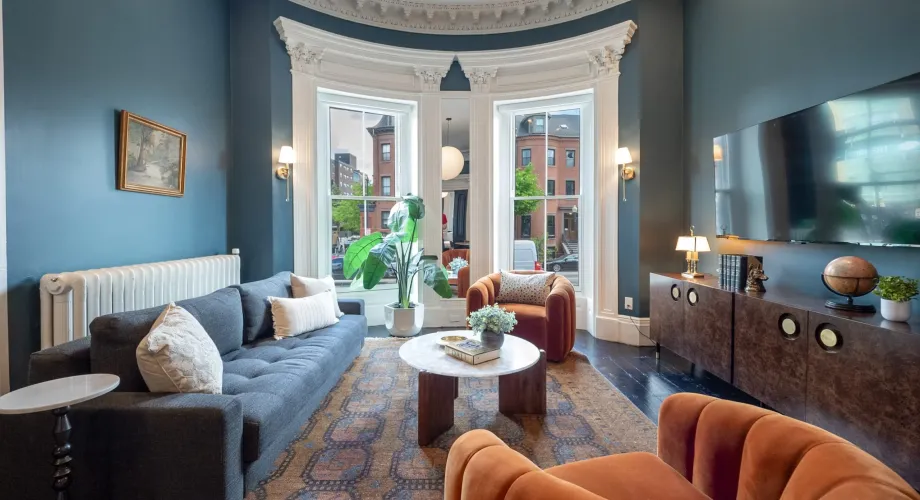 Living room with blue walls, bay windows, a sofa, and orange armchairs