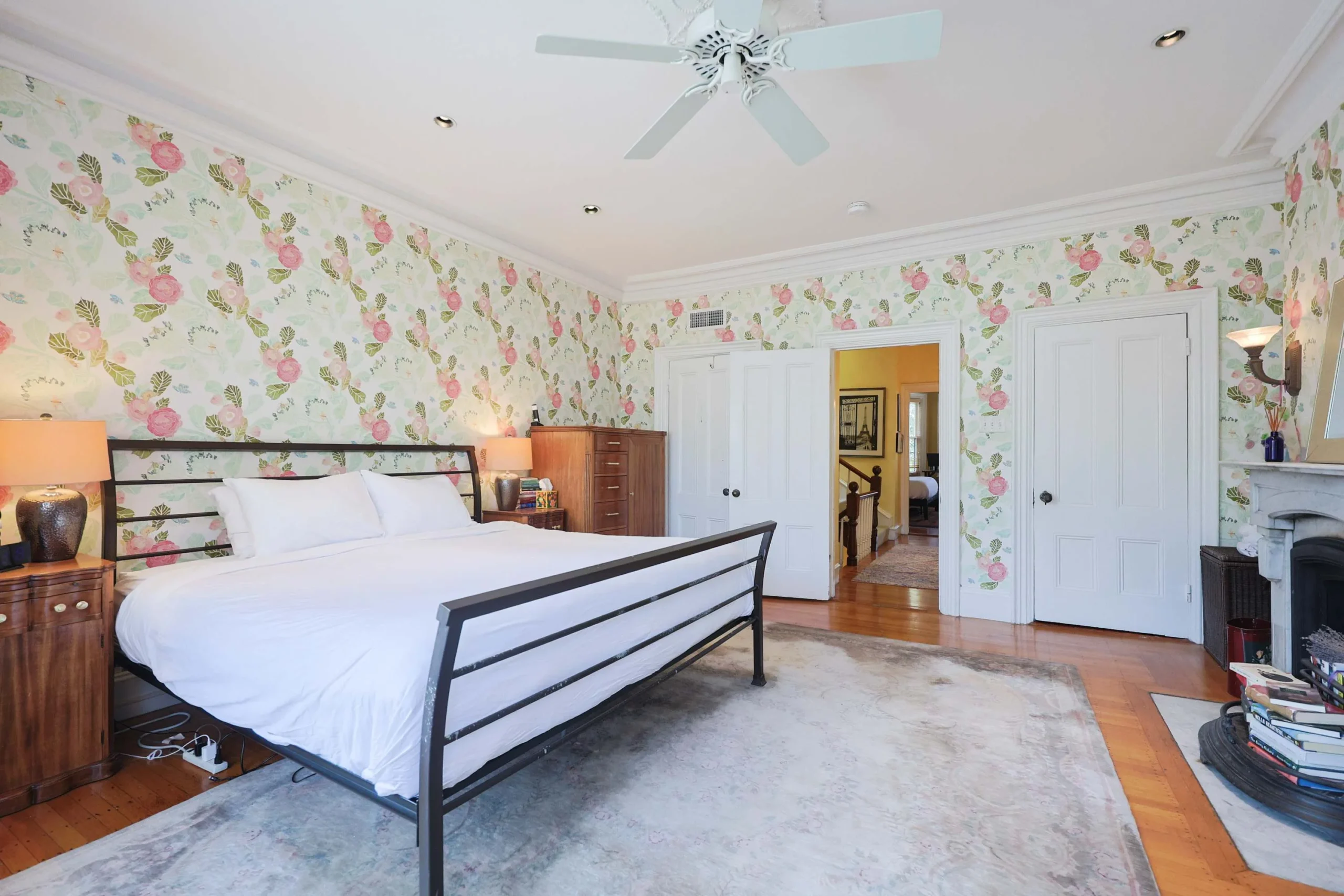 Elegant bedroom with metal-framed bed, white linens and floral rose wallpaper in a Boston brownstone rental with parking