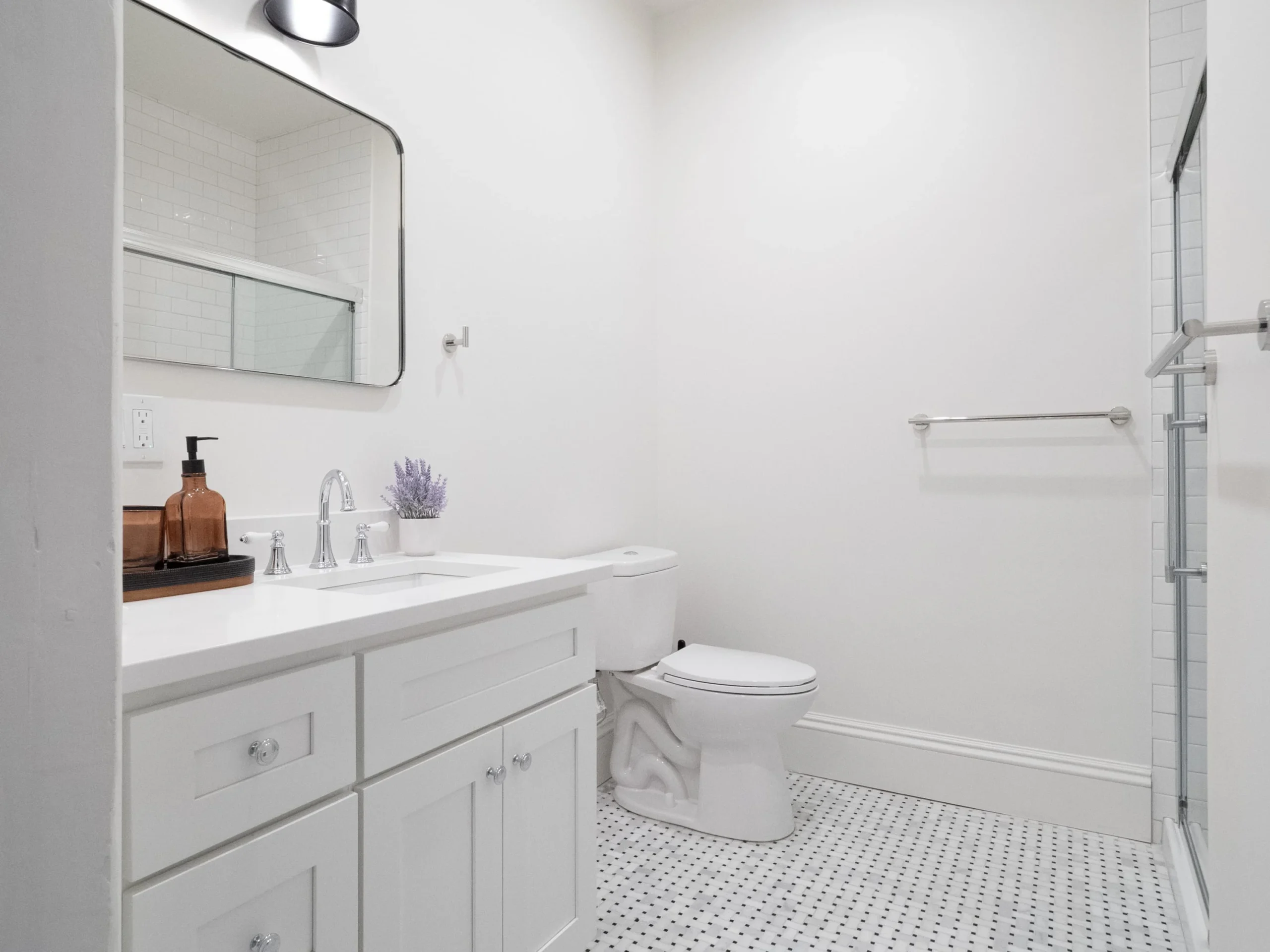Bright modern bathroom with white cabinetry, subway tile walls, marble vanity, and walk-in shower in a Boston, MA rental by